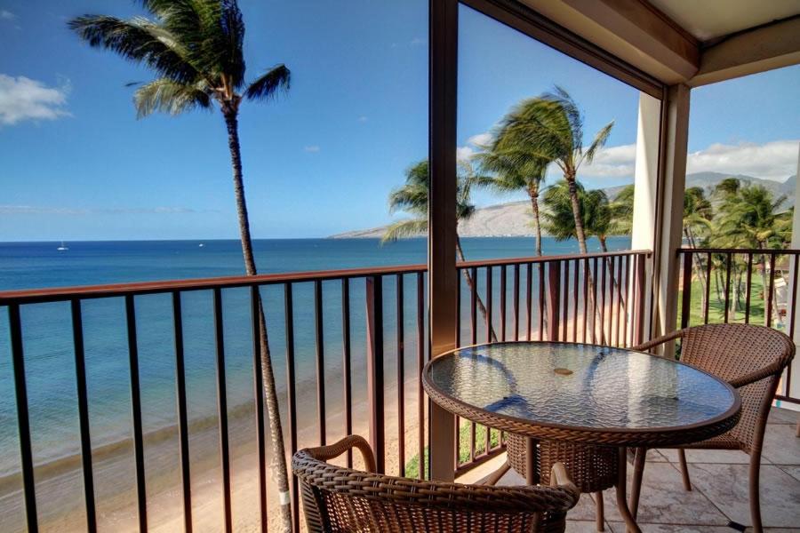 a table and chairs on a balcony overlooking the beach at KIHEI BEACH, #506^ condo in Kihei