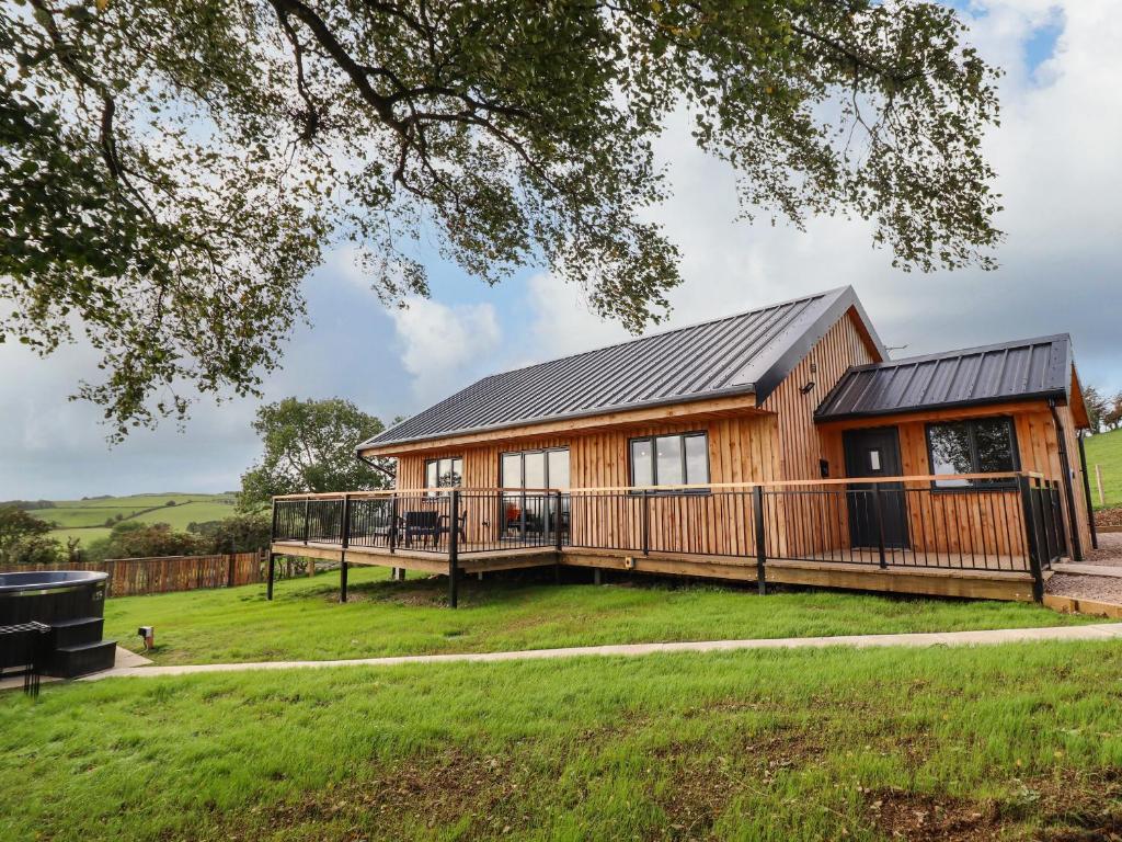 uma casa de madeira com um grande deque e uma casa em Mynydd Y Glyn Lodge em Llanfyllin