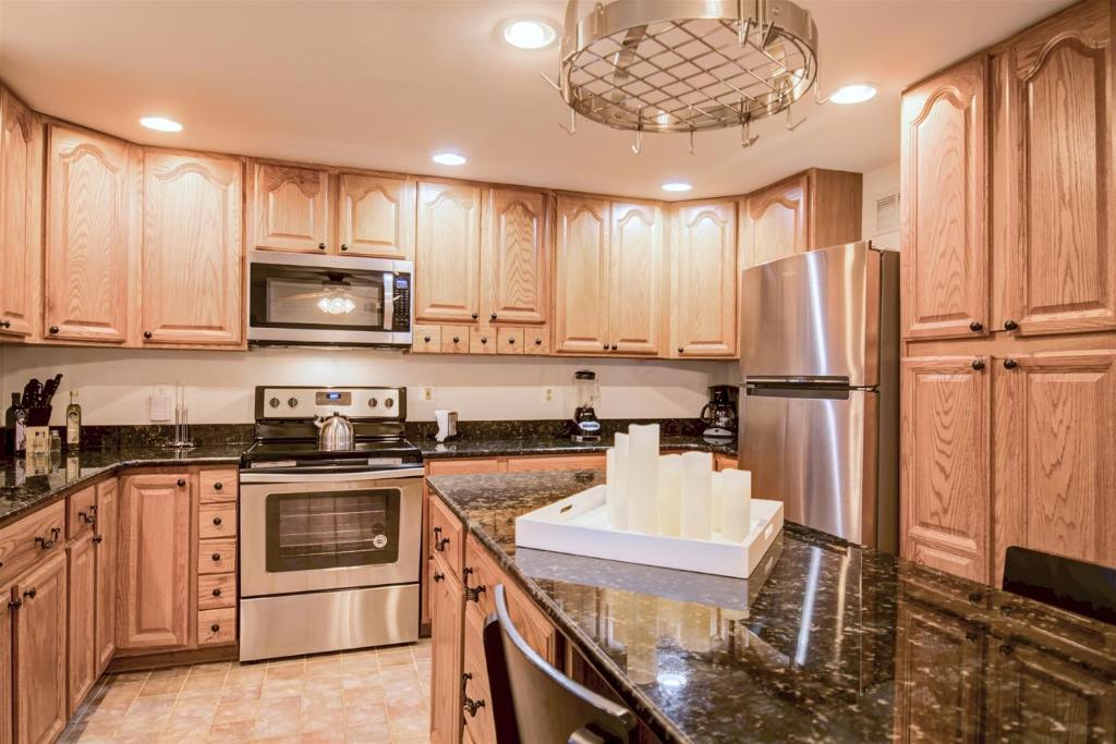 a kitchen with wooden cabinets and stainless steel appliances at Spacious 3-story Townhome 40 Minutes from DC Pet-Friendly, Fast WiFi, Perfect in Sterling