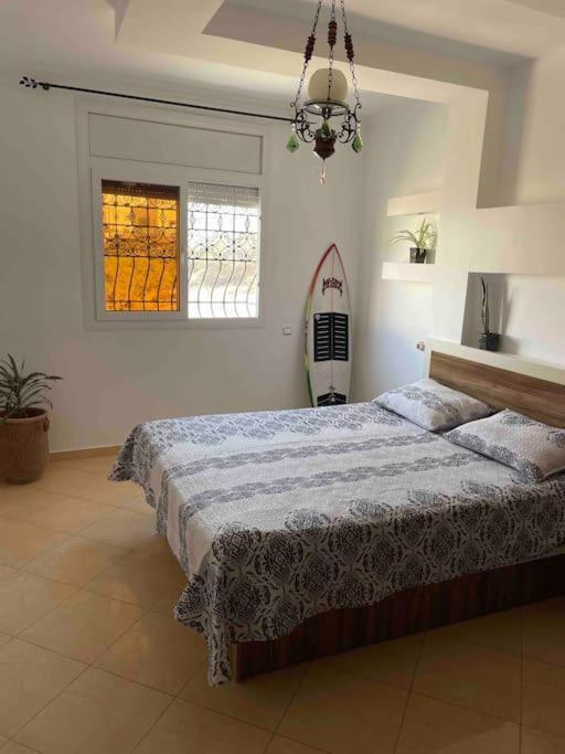 um quarto com uma cama e uma prancha de surf em Apartment Oufella em Tamraght Ouzdar