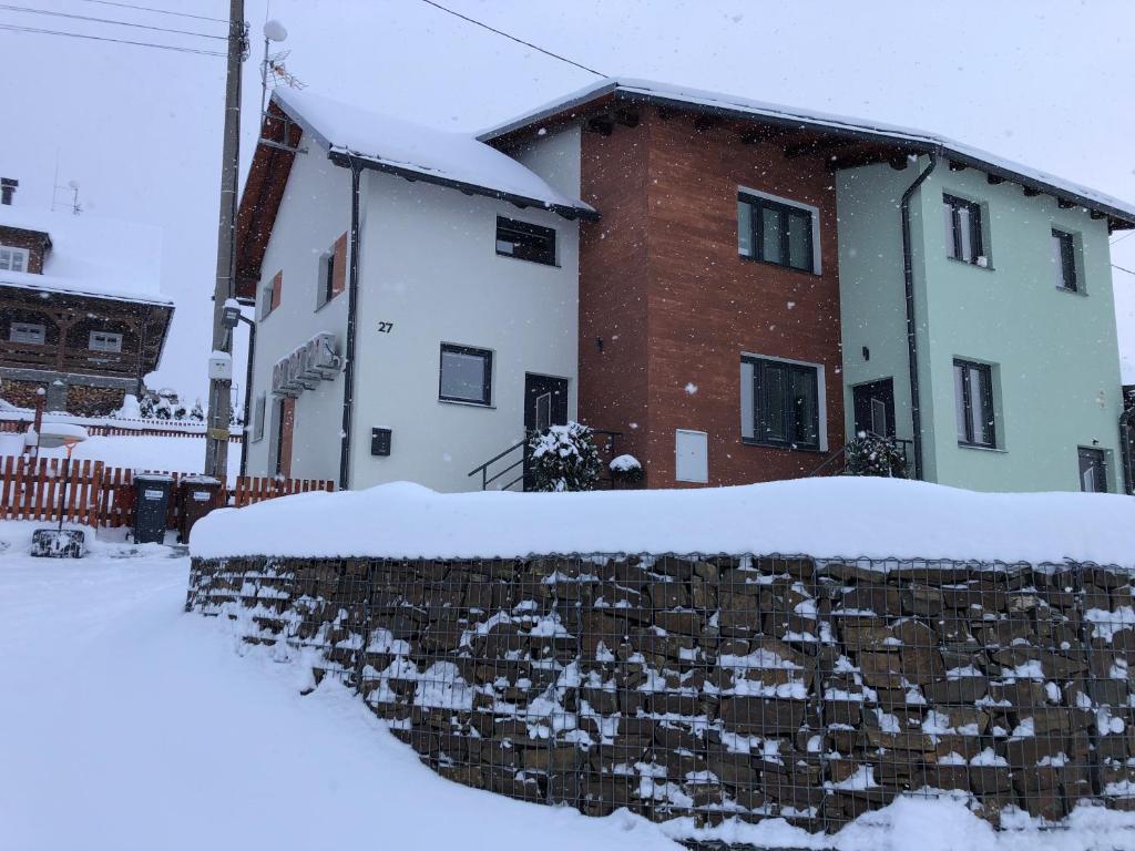 uma parede de pedra em frente a uma casa coberta de neve em Rodinný penzion MARMAR em Staré Město