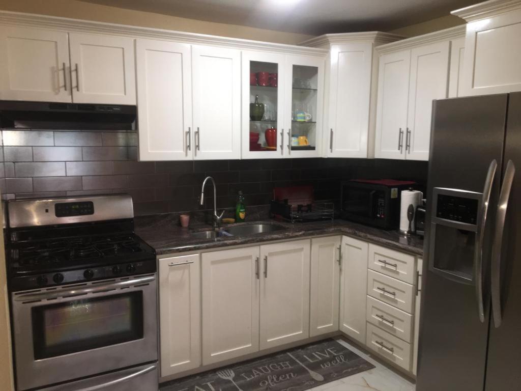 a kitchen with white cabinets and a stainless steel refrigerator at Apartment in Montego Bay, St James - Fully Equipped For Long Term Stays in Montego Bay