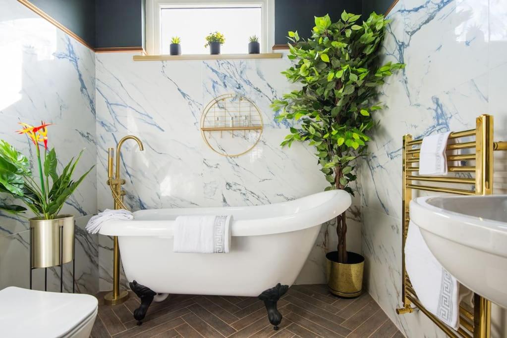 a bathroom with a white tub and a sink at Lux Versace Pad Sleeps 10 Hot Tub, Cinema & Games Room in London