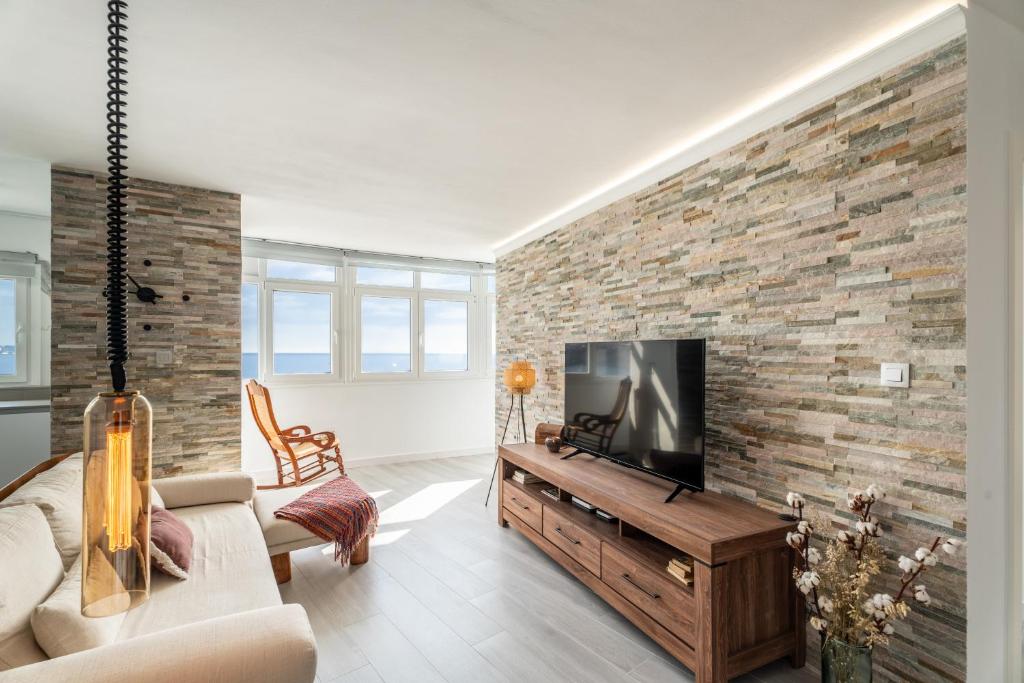 a living room with a tv and a brick wall at Susurros del Mar Sunset in Santa Cruz de Tenerife