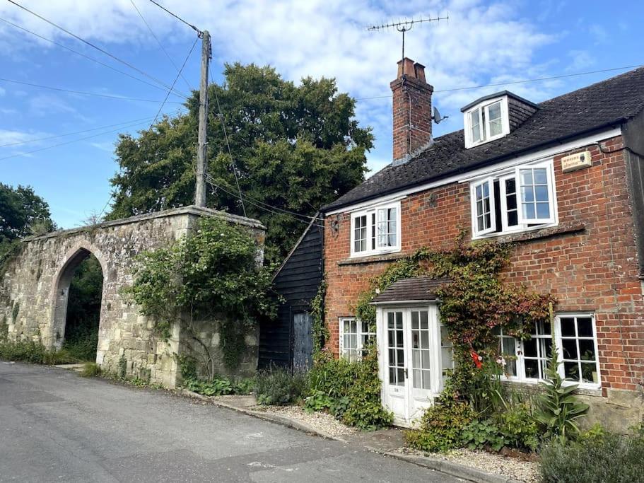an old brick house with an archway on a street at Charming artist’s cottage in East Knoyle