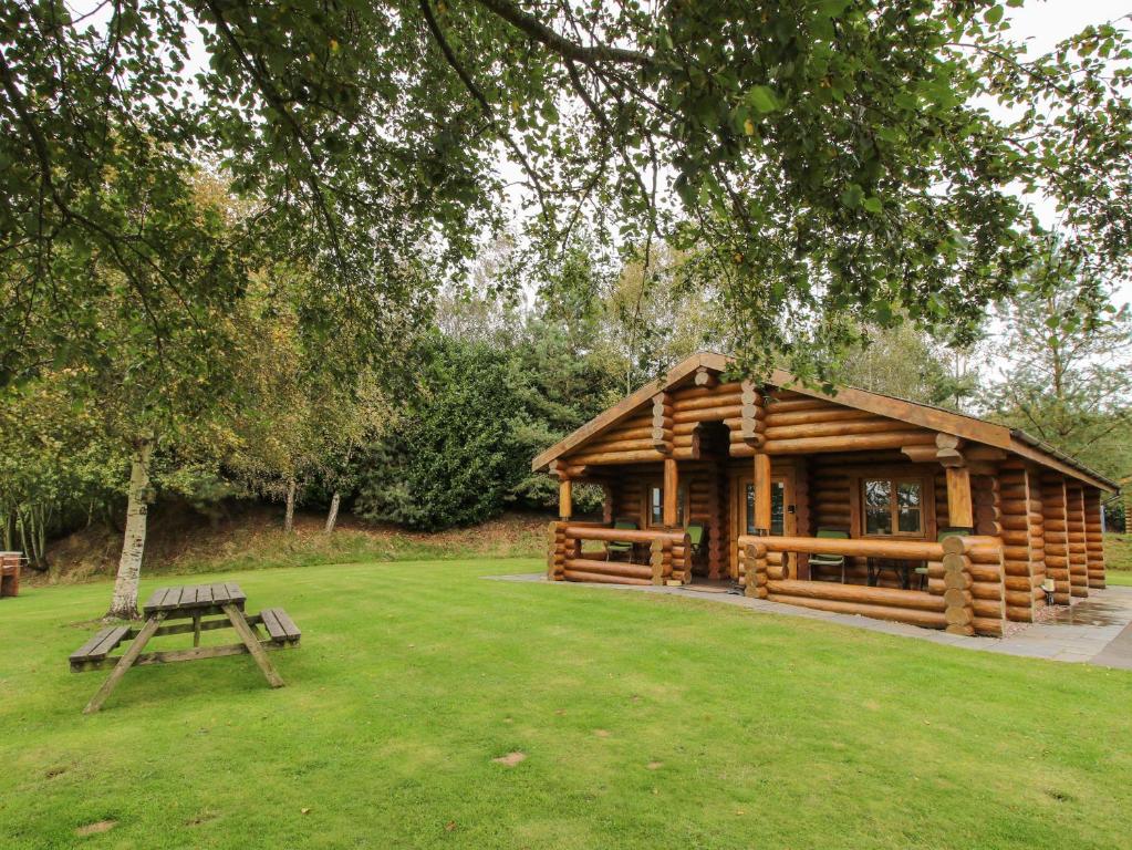 a log cabin with a picnic table in the grass at Brynallt Country Park in Ellesmere