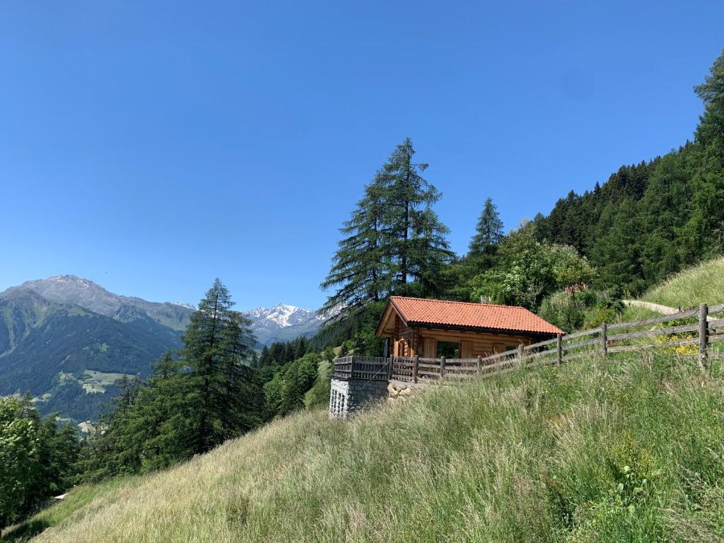 eine Hütte auf einem Hügel mit Bergen im Hintergrund in der Unterkunft Chalet Leitn-Anger in St. Leonhard in Passeier