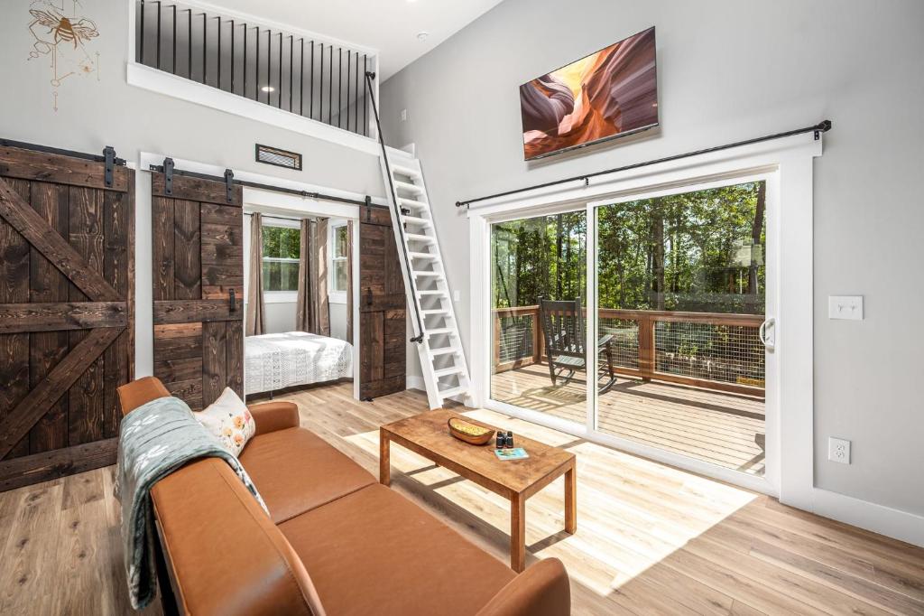 a living room with a couch and a sliding glass door at NEW Beehive Tree House Retreat in Pittsboro