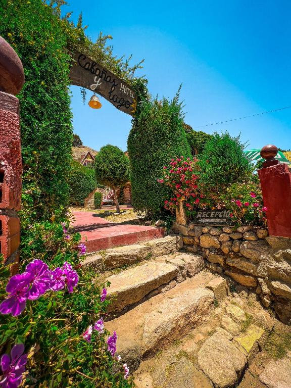 un jardín con flores y un cartel que lee el carril de trébol en Hostal Sol y Lago, en Copacabana