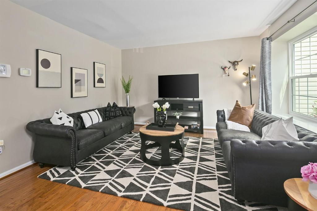 sala de estar con sofás de cuero negro y TV en 4BR Townhome, Close to Shops & Restaurants, 40 Mins to DC, en Sterling