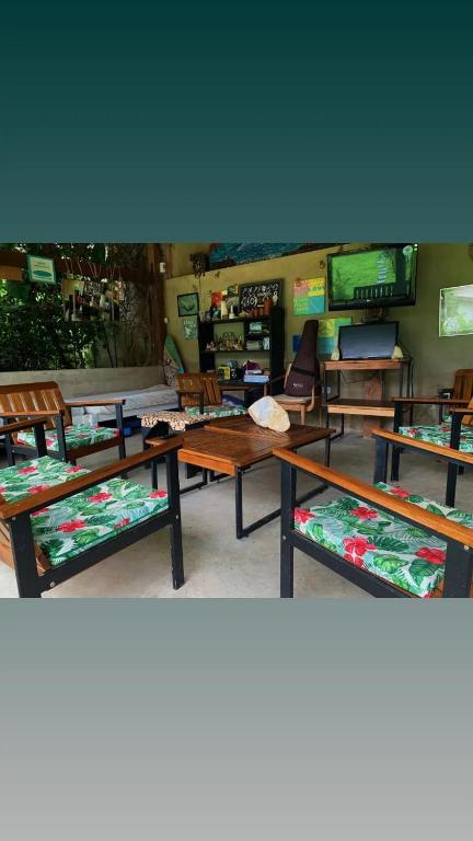 a room with tables and chairs and a tv at Farah Hostel Suítes Camping Smartcamp e Passeio de barco in Boicucanga