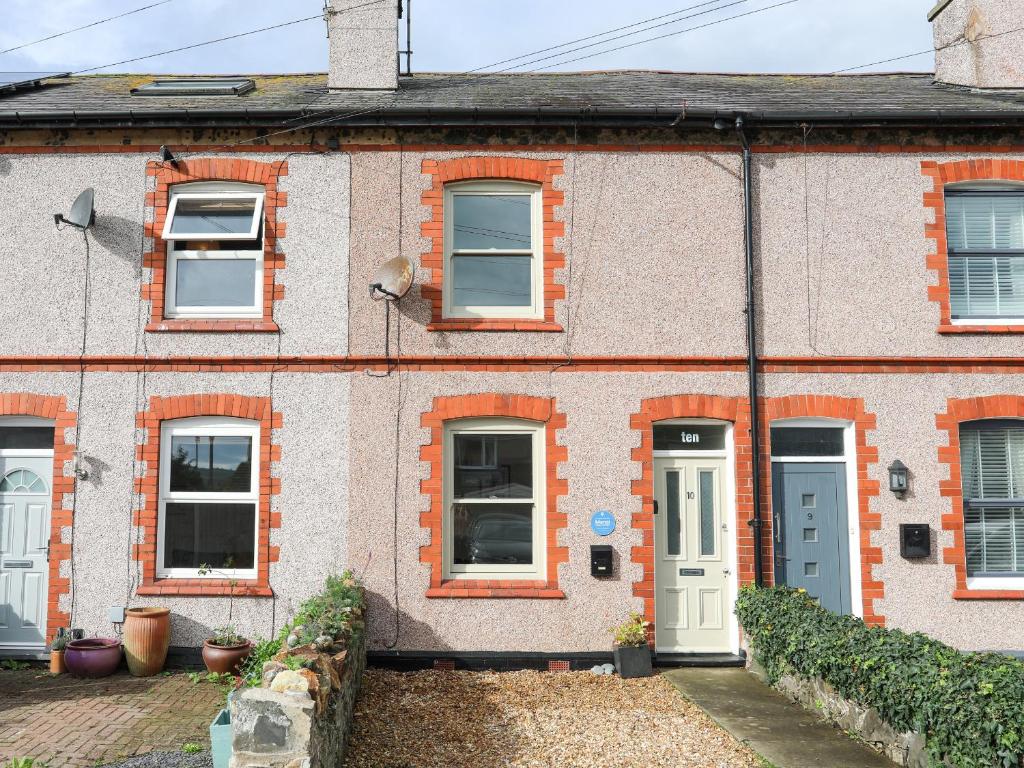 a brick house with a white door and windows at Shamrock Cottage in Conwy