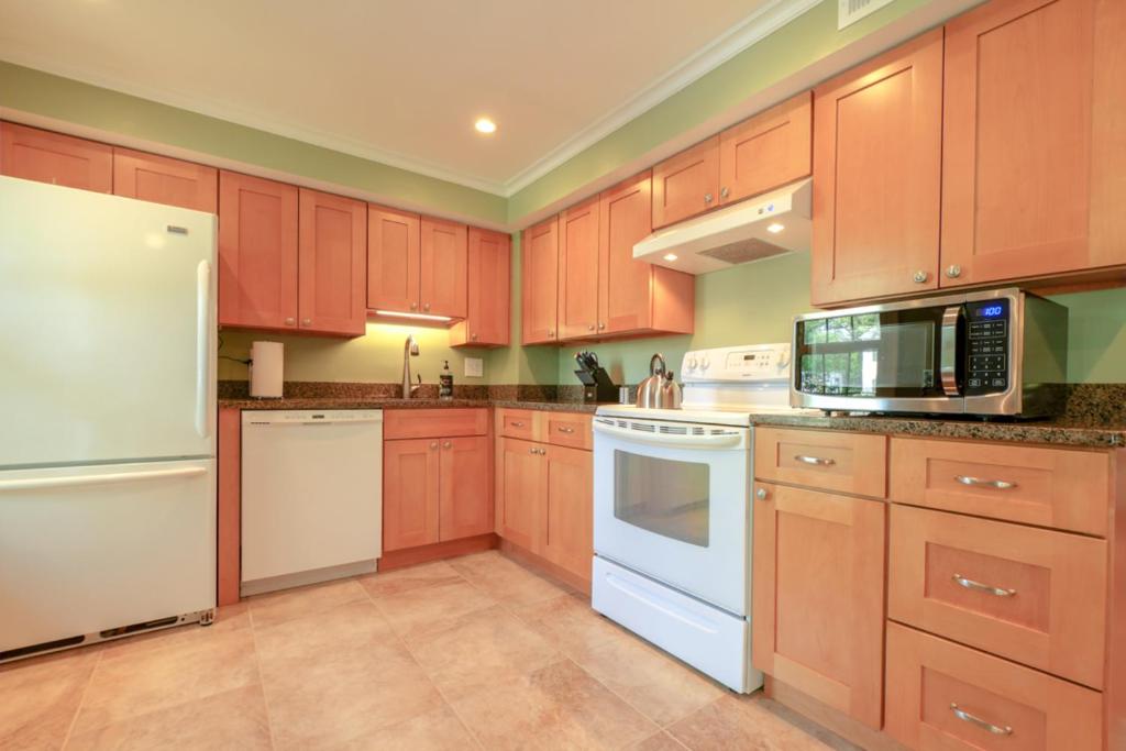 una cocina con armarios de madera y electrodomésticos blancos en NEW! 3-story Townhome - Private, Self checkin, Quiet. en Sterling