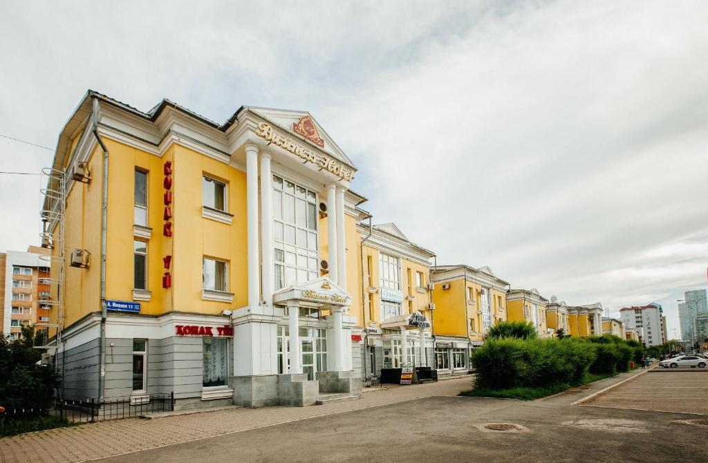 une rangée de bâtiments jaunes et blancs dans une rue dans l'établissement Business Hotel, à Astana