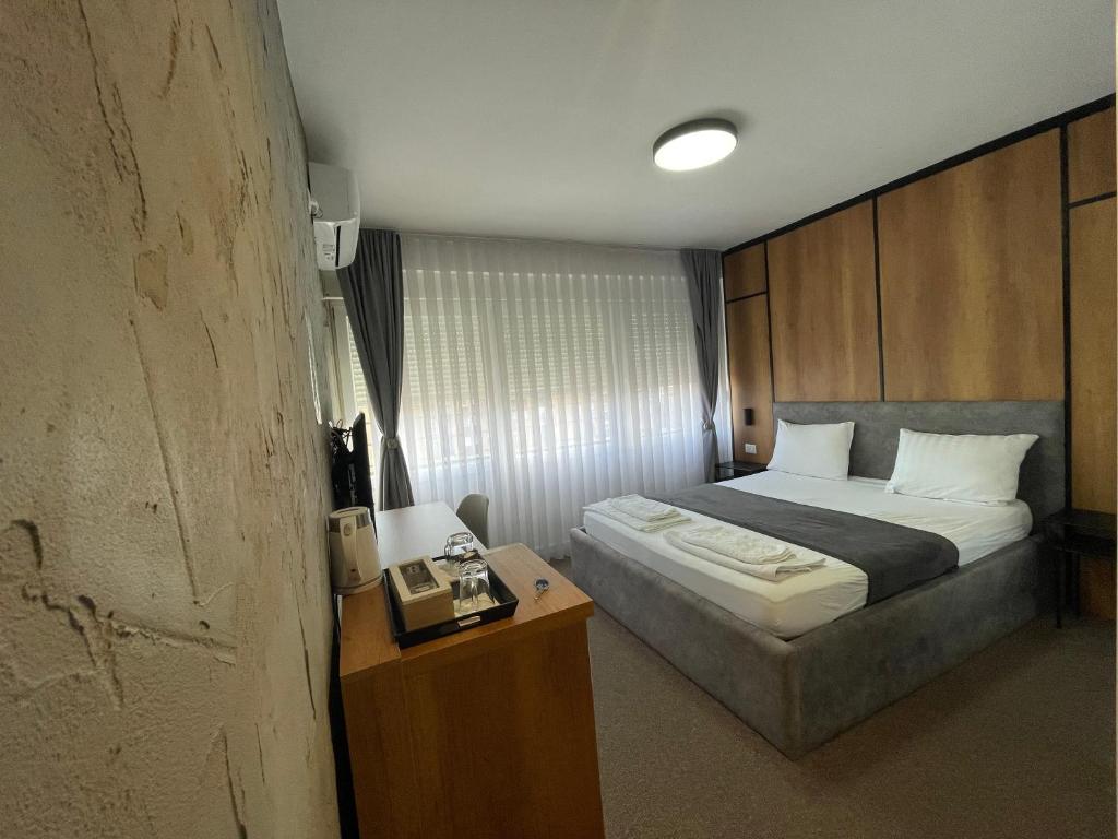 a bedroom with a bed and a night stand with a phone at New Prishtina Luxury Rooms in Pristina