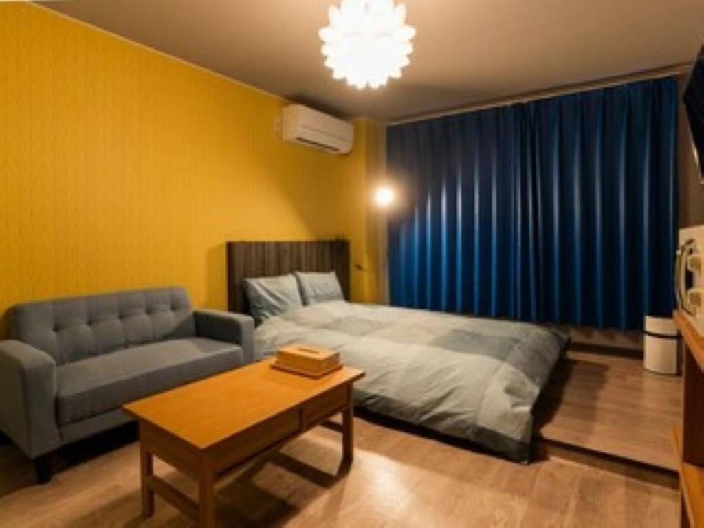 a bedroom with a bed and a couch and a table at InnCocoSumu？ - Vacation STAY 09843v in Kirishima
