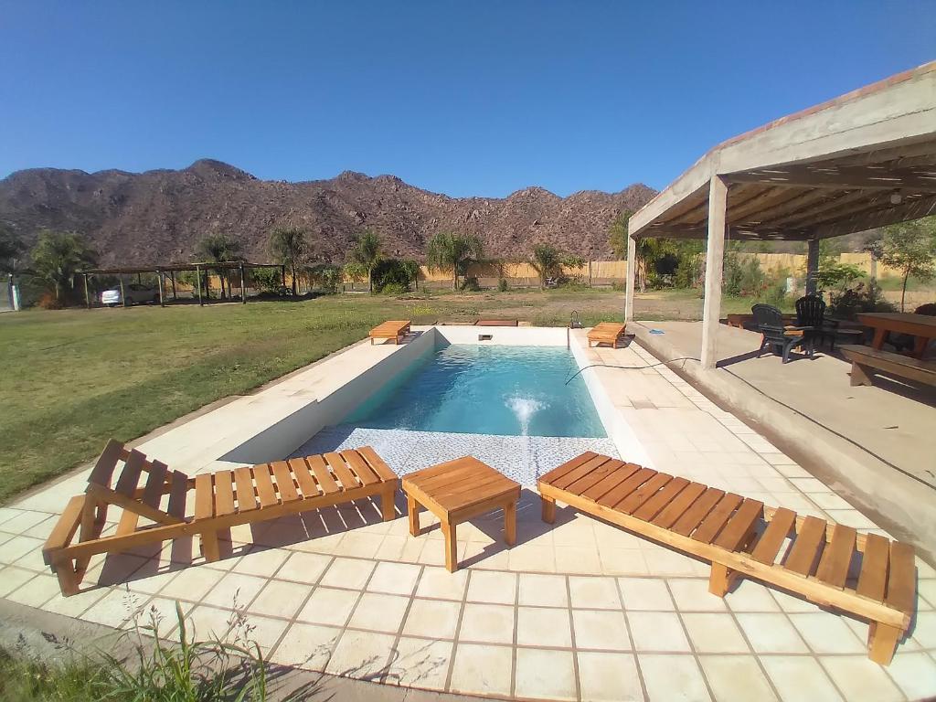 a swimming pool with two wooden benches next to it at Cuesta de san miguel in Chilecito