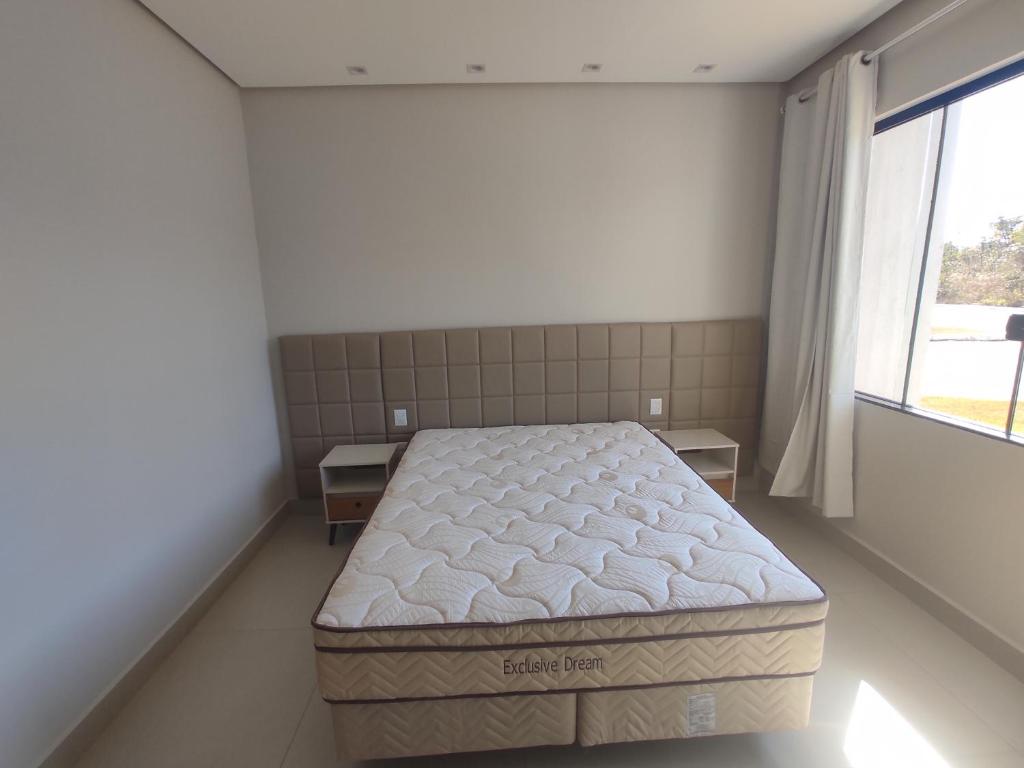 um quarto com uma cama grande e uma janela em Casa Brisas do Lago em Capitólio