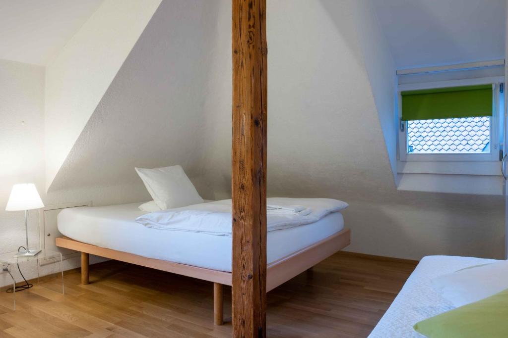 a bed with a wooden post in a room at Hotel Marthahaus in Bern