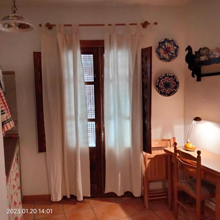 a room with a window with white curtains and a table at Apartamento vacacional en la Alpujarra in Laroles