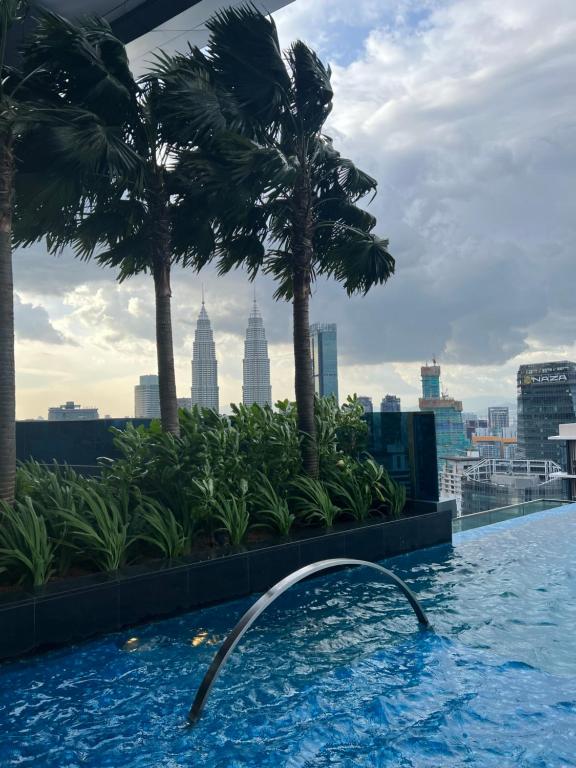 a swimming pool on the roof of a building with palm trees at Eaton Residence KLCC BY Galaxy Suites in Kuala Lumpur