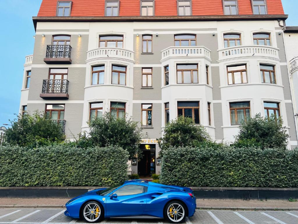 Gatsby Hotel - Adults Only - Small Luxury Hotel - by F-Hotels في بلانكنبرخ: سيارة زرقاء متوقفة أمام مبنى