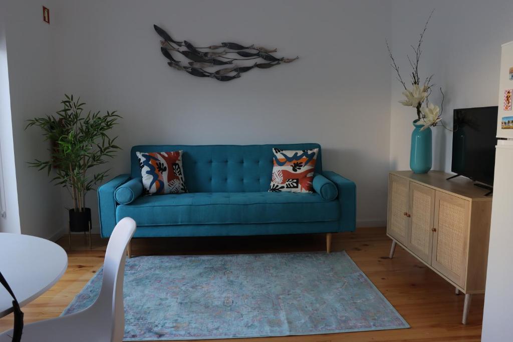 een blauwe bank in een woonkamer met een tv bij A Casa da Joana in Aveiro