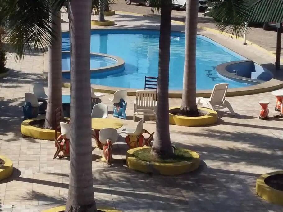 - une piscine bordée de palmiers, de tables et de chaises dans l'établissement Chalé em Barreirinhas - MA, à Barreirinhas