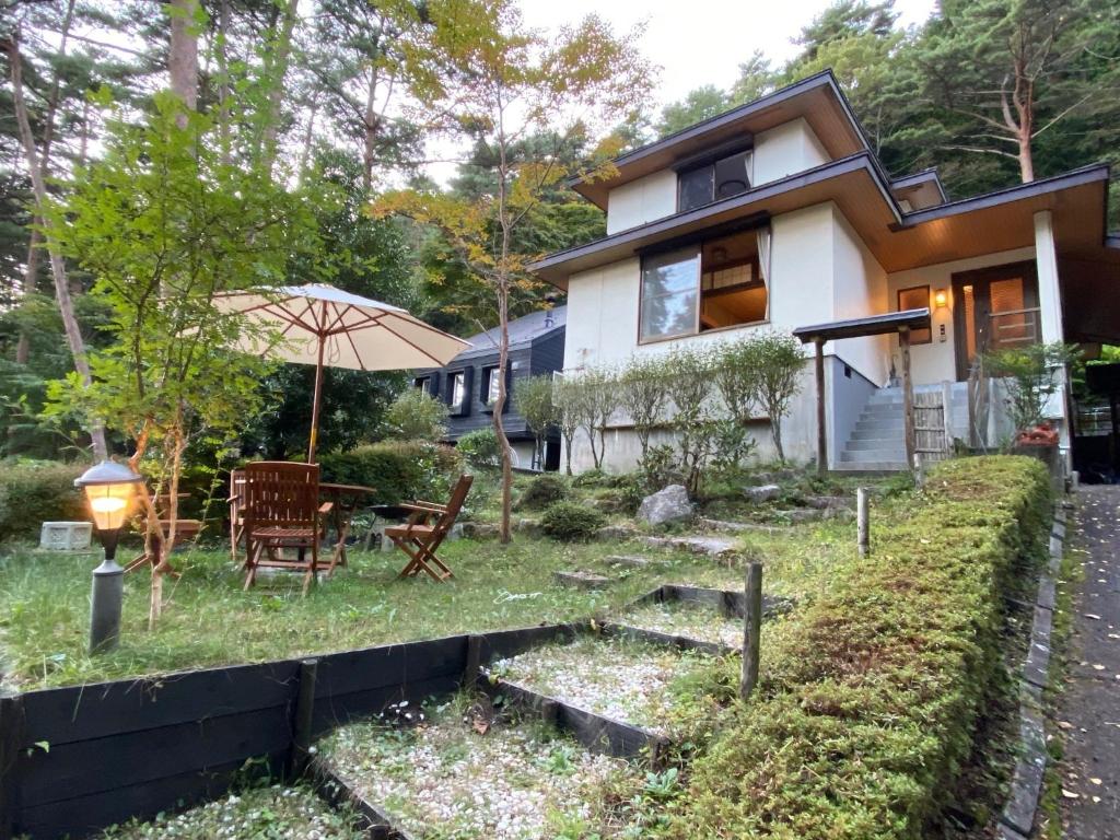 una casa con una mesa y una sombrilla en el patio en [Luxury villa with BBQ facilities overlooking Moun - Vacation STAY 14273, en Oishi