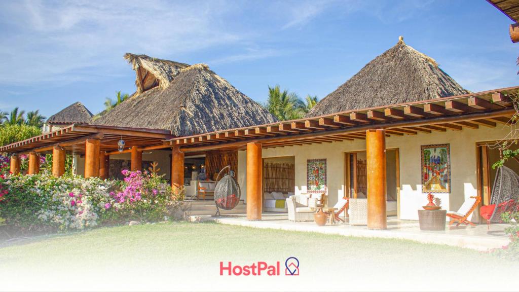 a resort with thatched roofs and chairs and flowers at Beautiful Family House Beachfront 