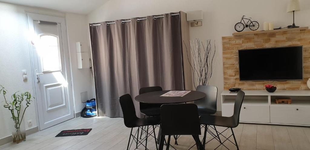 uma sala de estar com uma mesa e cadeiras e uma televisão em Studio calme em Mitry-Mory