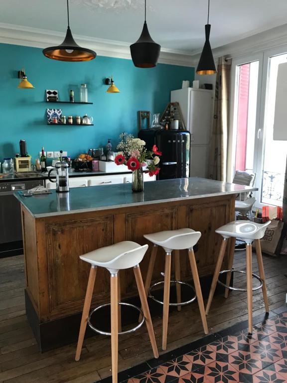 una cucina con isola in legno e 3 sgabelli da bar di Maison proche stade de France et village olympique a Enghien-les-Bains