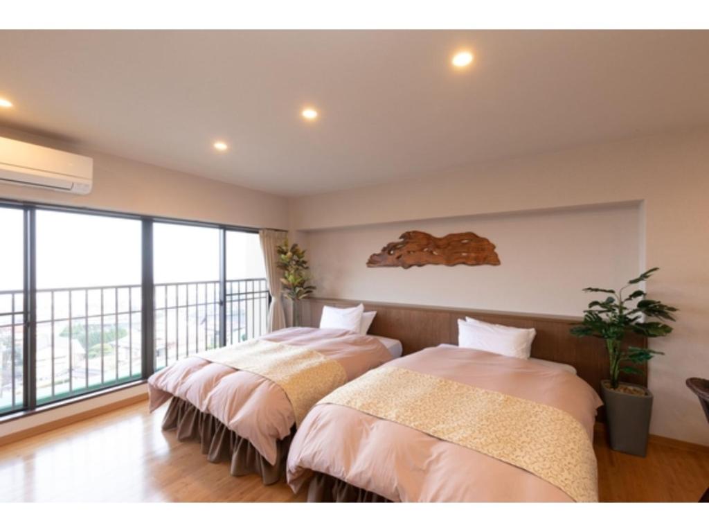 two beds in a room with a balcony at 〜Ｇｒａｎｄｐｉａ Ｒｅｓｏｒｔ ＯＵＧＩＹＡＭＡ〜 - Vacation STAY 51006v in Beppu