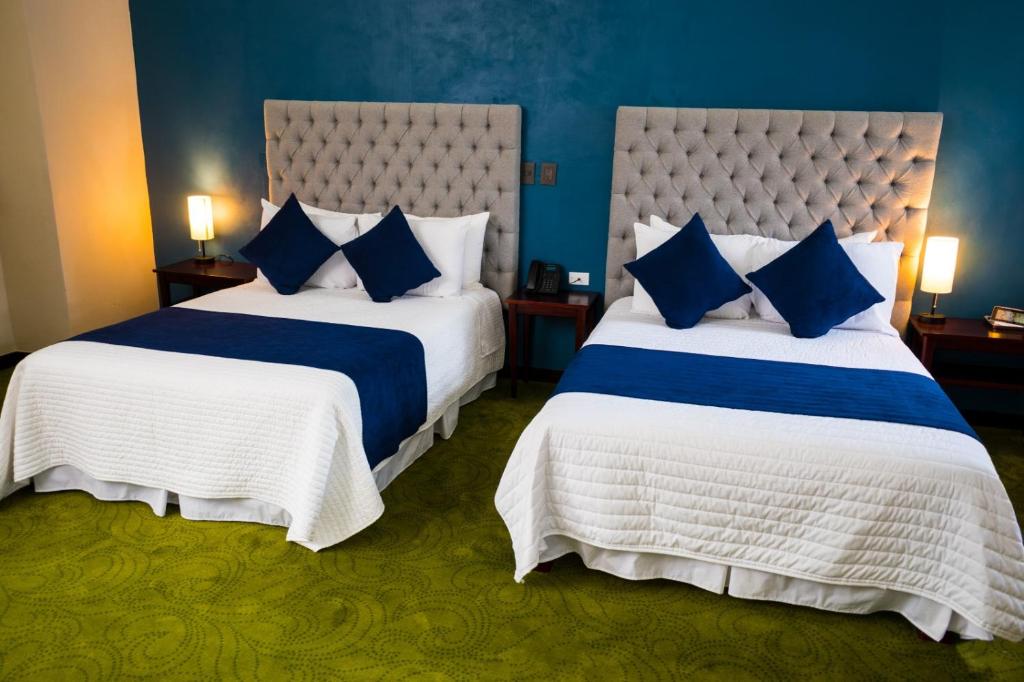 2 letti in una camera d'albergo con pareti blu di HOTEL MARGARITA a Puebla
