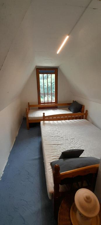 1 dormitorio en el ático con 2 camas y ventana en Chata na konci světa, en Chladno