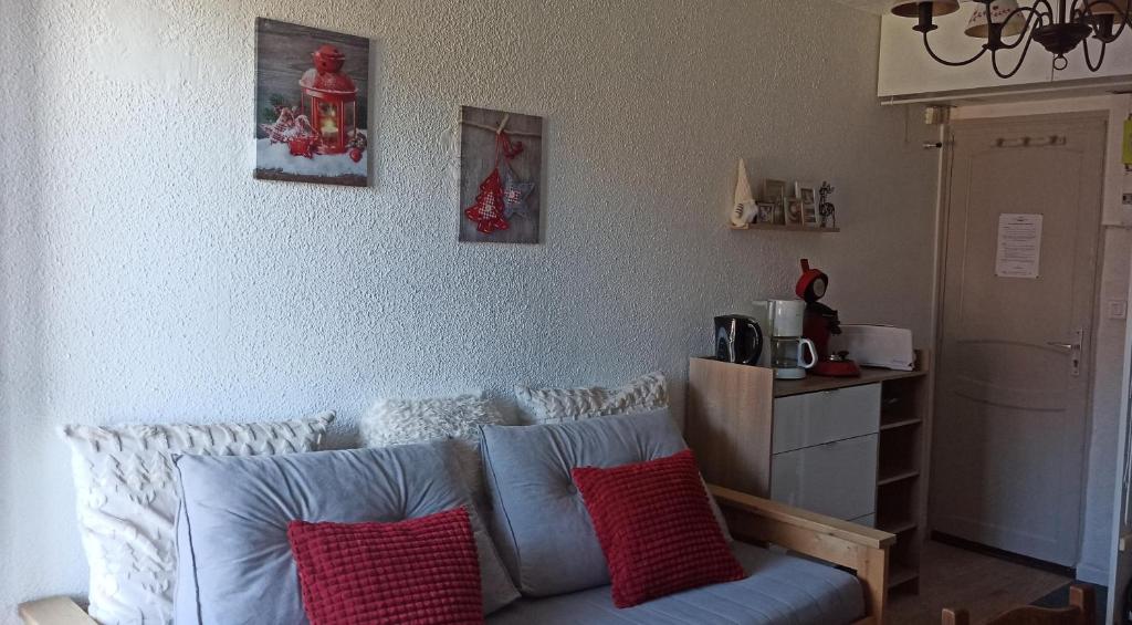 a living room with a blue couch with red pillows at Ustou Guzet neige, appartement de 32 M2 avec balcon dans les Pyrénées aux pieds des pistes in Ustou