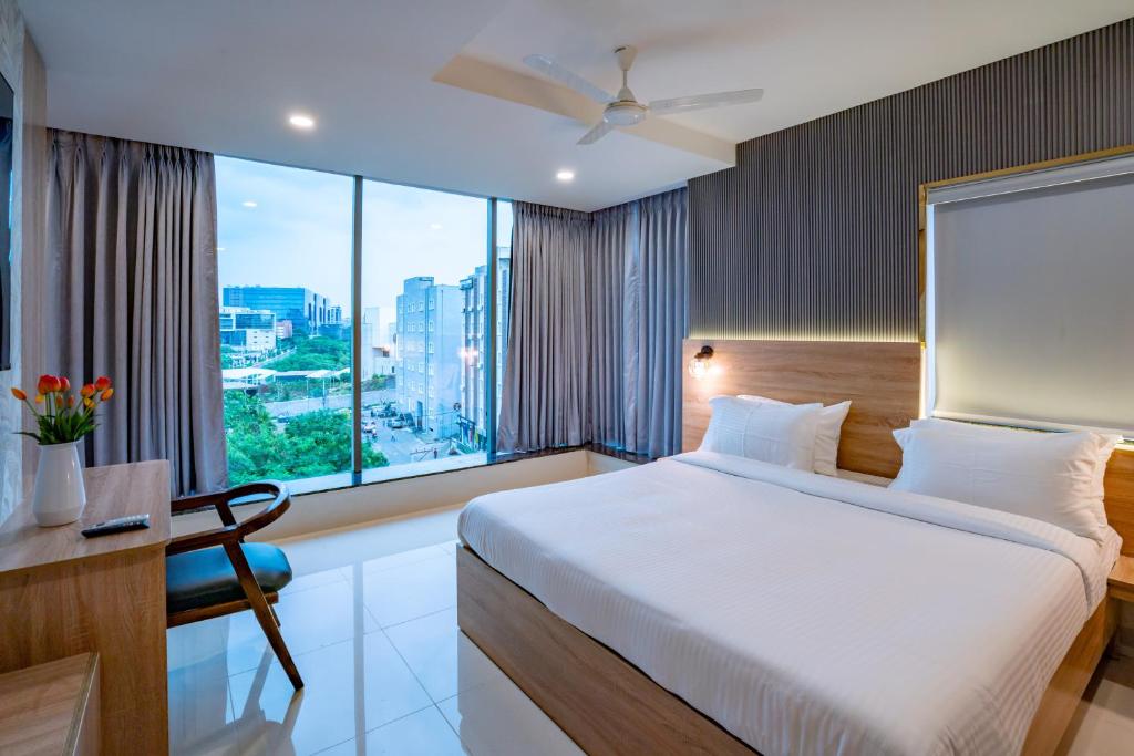 a bedroom with a bed and a desk and a large window at Harvey's Hotels (Gachibowli) in Hyderabad