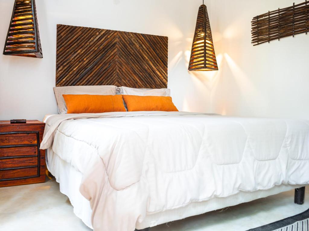 1 dormitorio con cama blanca y cabecero de madera en EKOPARQUE LUNAFOREST, en Arroyo de Piedra