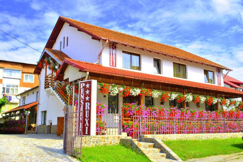 a building with a fence and flowers in front of it at Pensiunea Ruxi in Curtea de Argeş