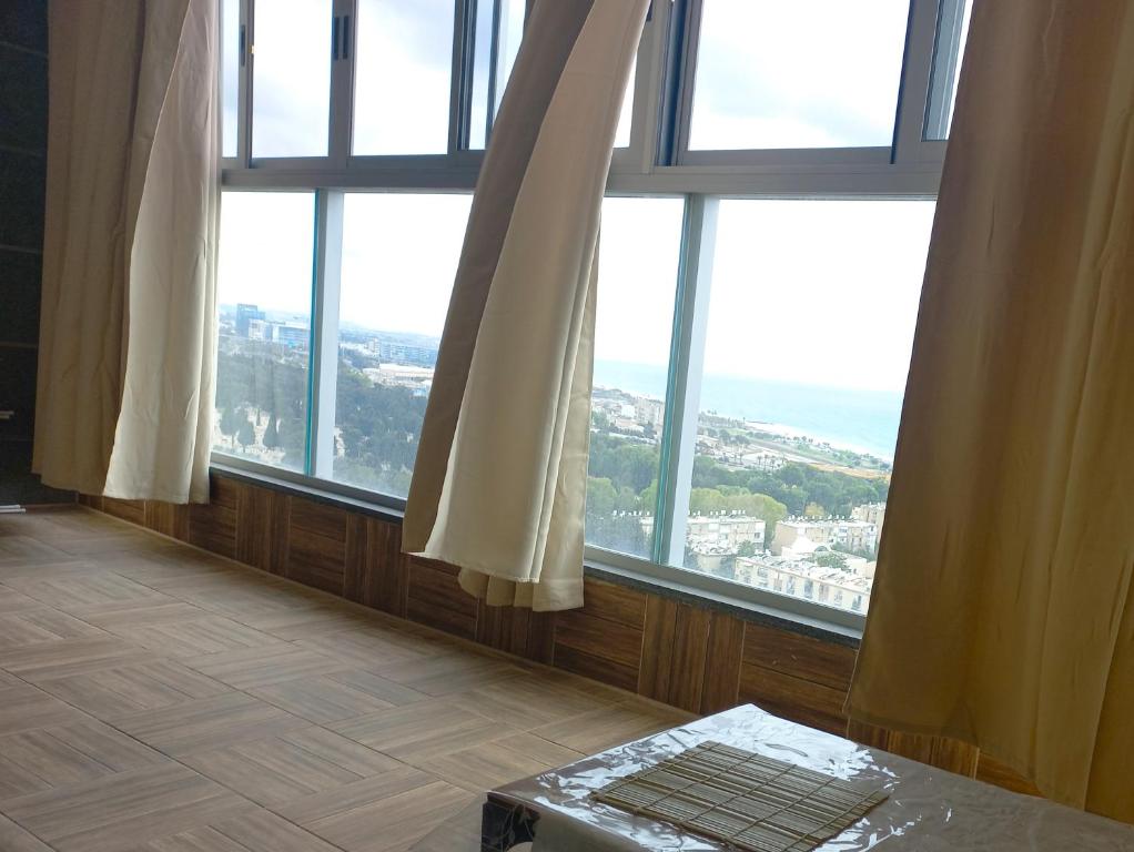 a room with large windows with a view of a city at Unique Luxurious New 4BR near Beach in Haifa