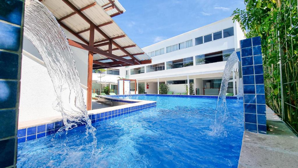a swimming pool with two fountains in front of a building at Brisa do Mar Praia Hotel in Morro de São Paulo