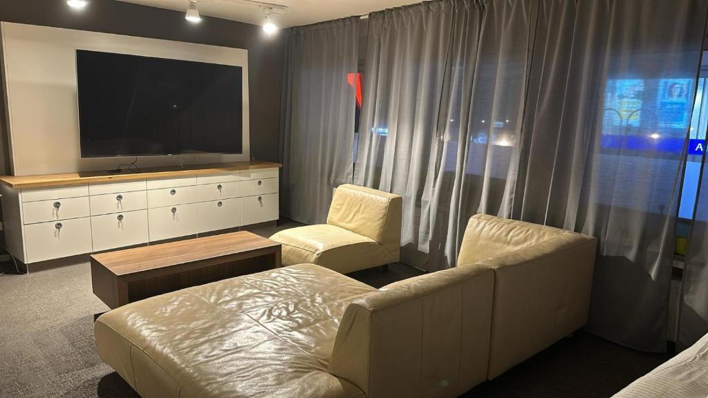 a living room with a tv and a couch and chair at SleepWell100 in Cologne