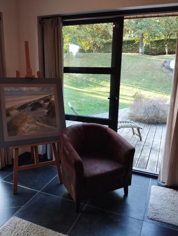 a chair sitting next to a painting in front of a window at VILLA KB&#39;HOME in Le Touquet-Paris-Plage