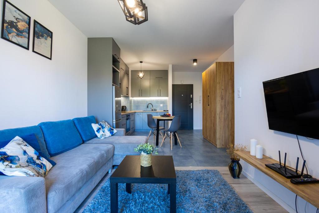 uma sala de estar com um sofá azul e uma televisão em Vip Apartament Wieniawskiego em Rzeszów
