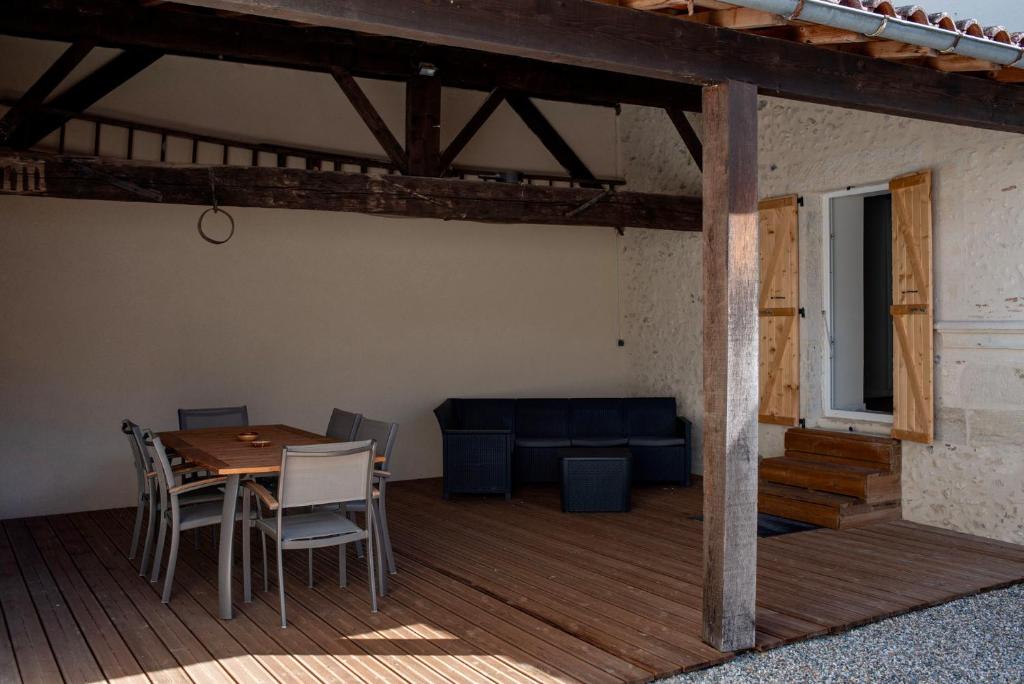 a wooden deck with a table and chairs and a couch at Au Coeur du Village Bassillac Périgueux in Bassillac