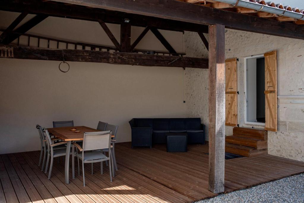 una terraza de madera con mesa, sillas y sofá en Au Coeur du Village Bassillac Périgueux, en Bassillac