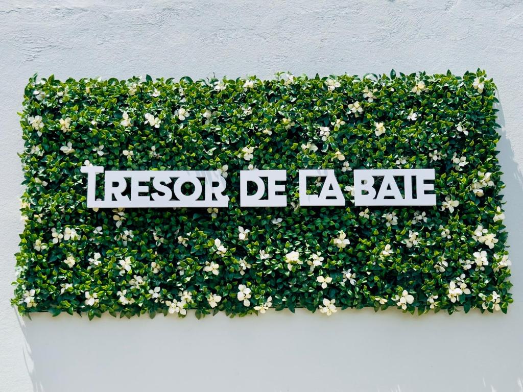 a sign in a hedge of flowers on a wall at Sublime Villa Piscine - Trésor de la Baie in La Trinité