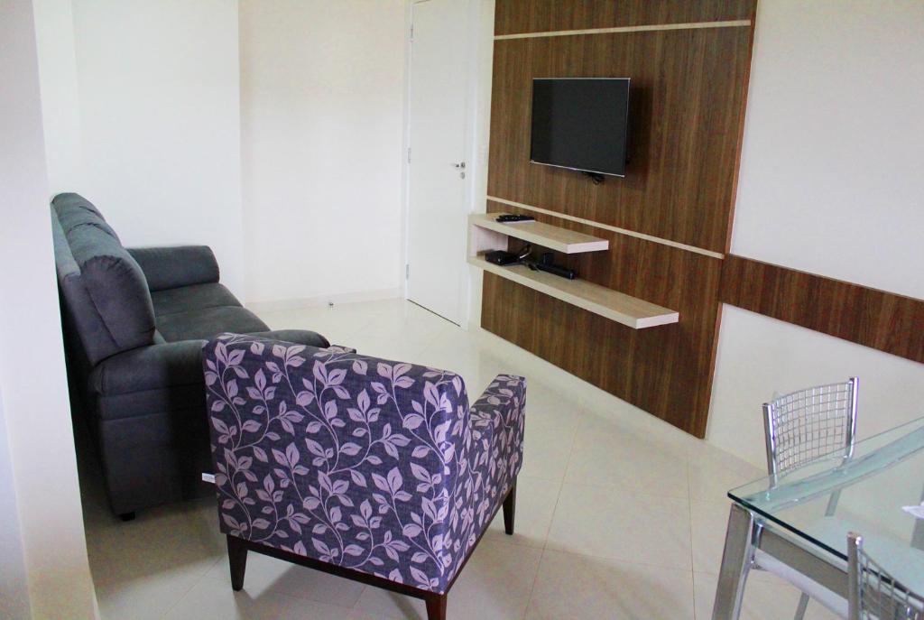 a living room with a chair and a tv at Encantos da Morada do Sol in Piratuba