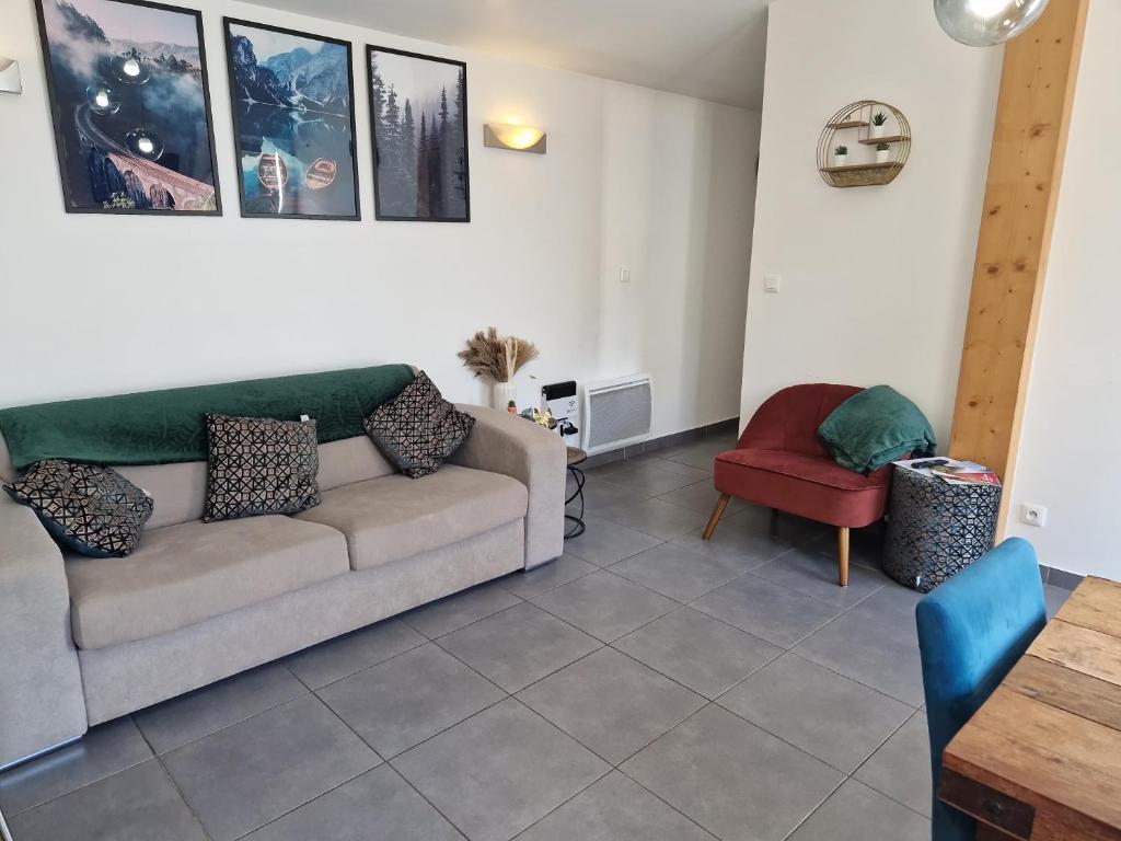 a living room with a couch and a red chair at La Meije, Chalets Reflets de Montagne in Le Bourg-dʼOisans
