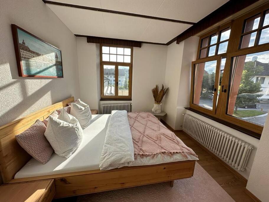 a bedroom with a large bed with two windows at Schönes Apartment in Schöftland in Schöftland